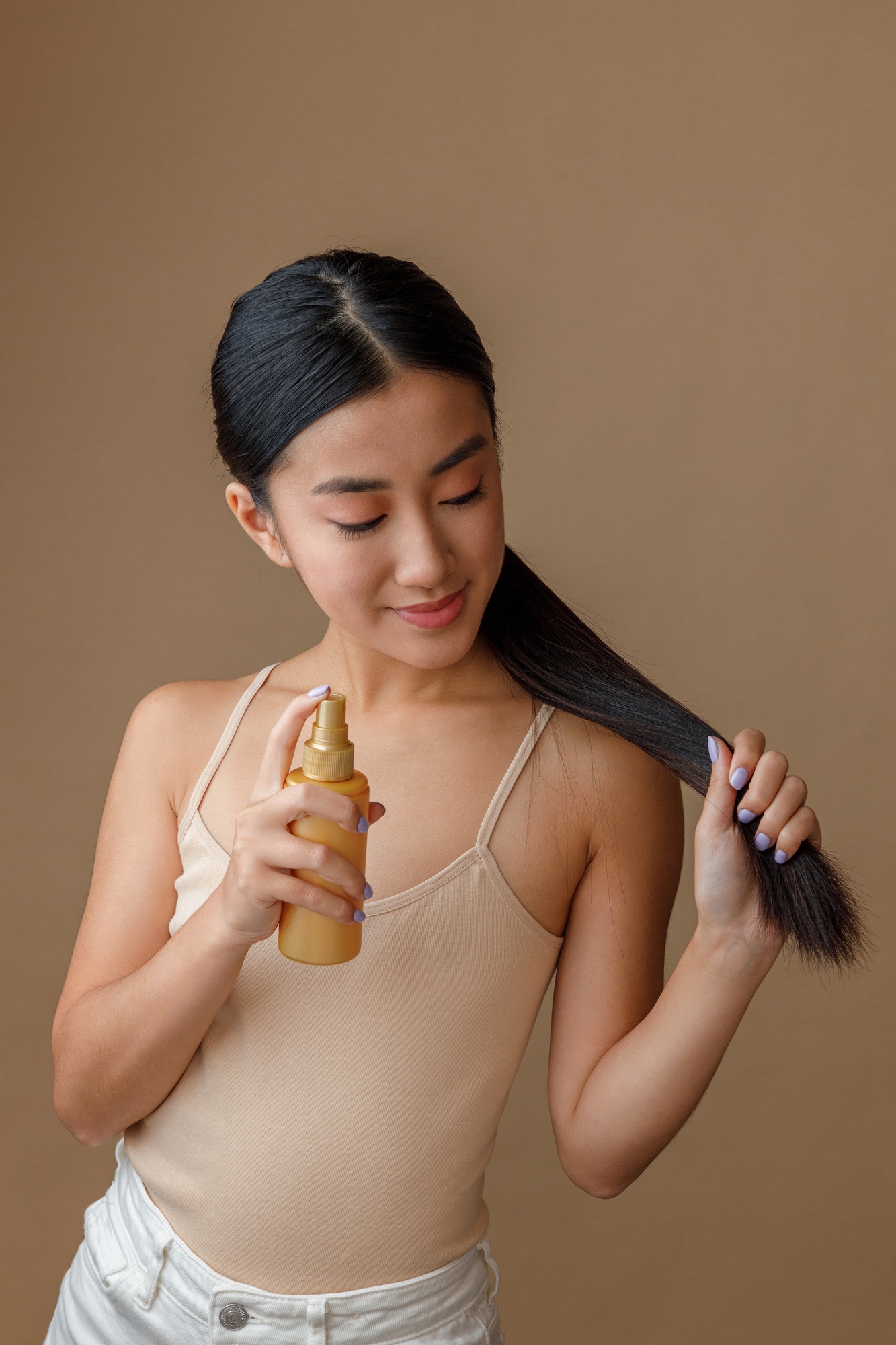 Asian young woman applying hair spray on her hair