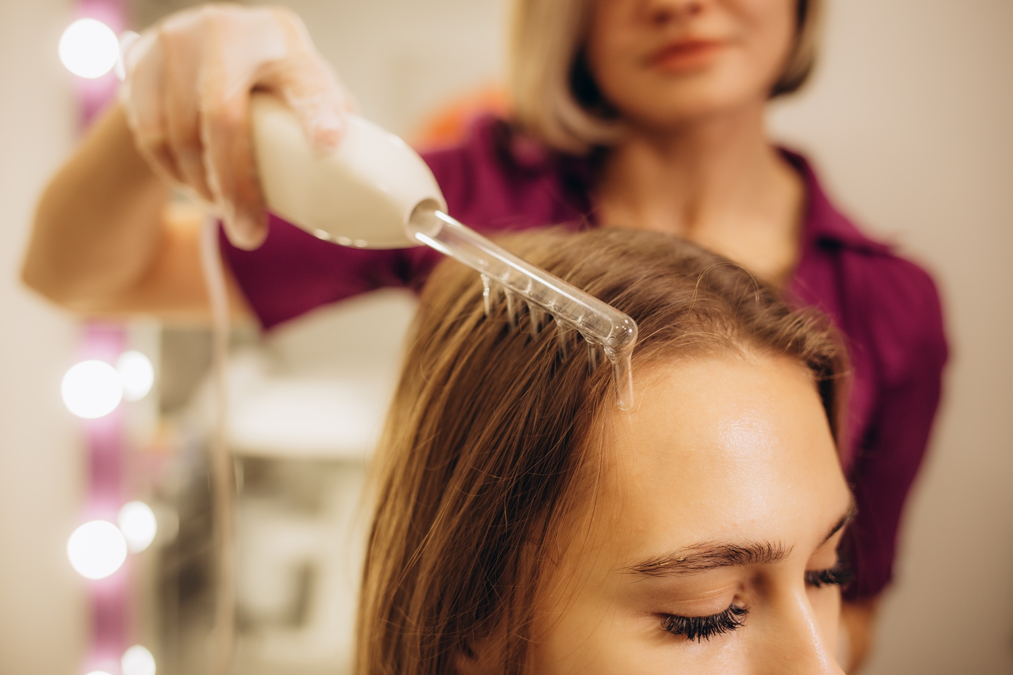 Beautician performs a professional procedure for the treatment of hair with darsonval