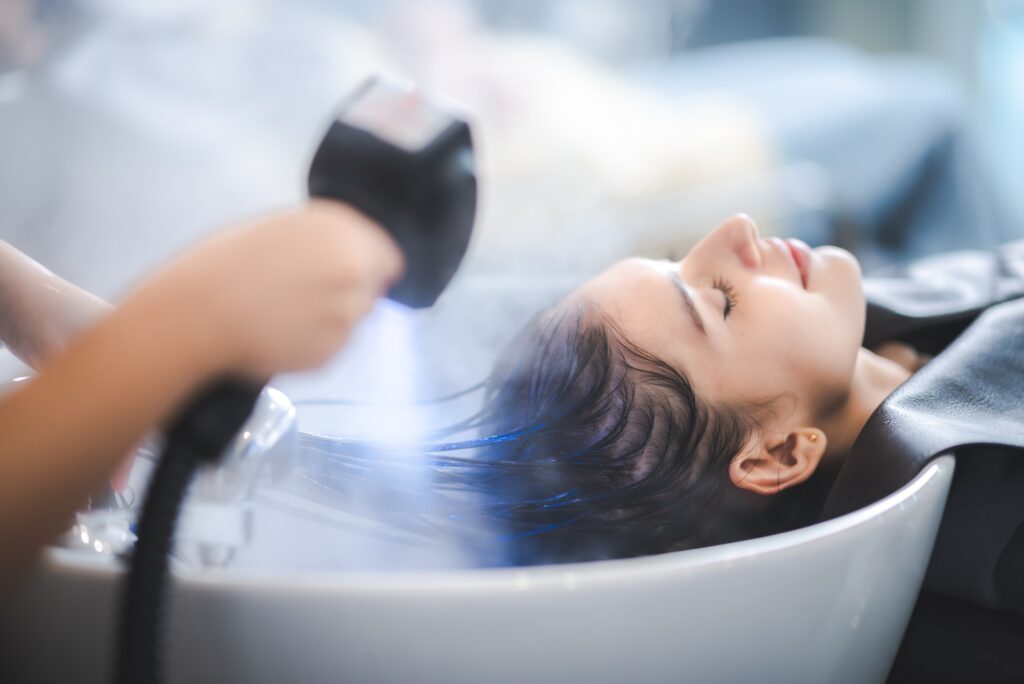 hairdresser washing client's hair at salon. happy young women customer relax and comfortable