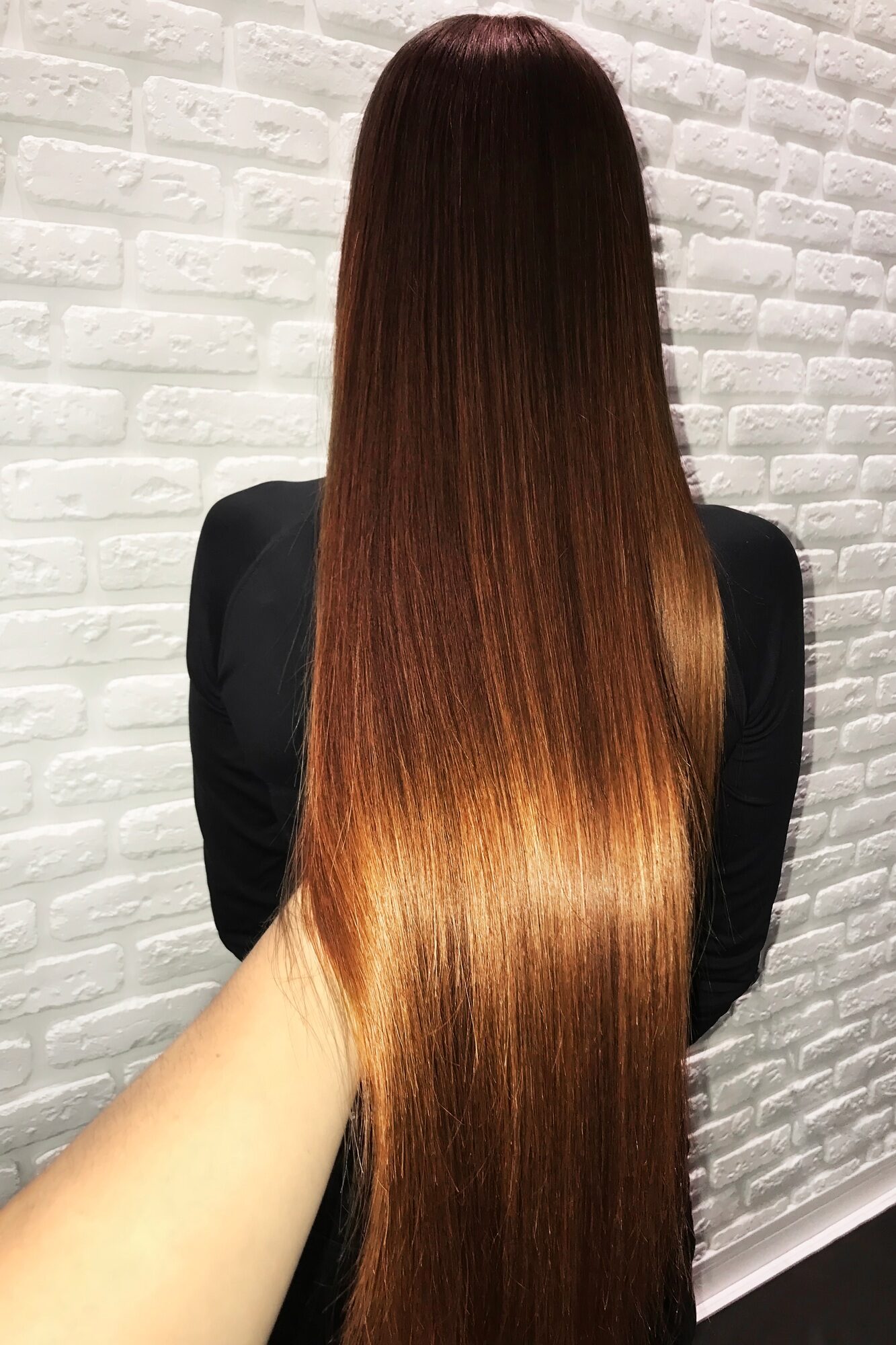 Hand Holding Long Brown Hair After Keratin Hair Restoration Procedure