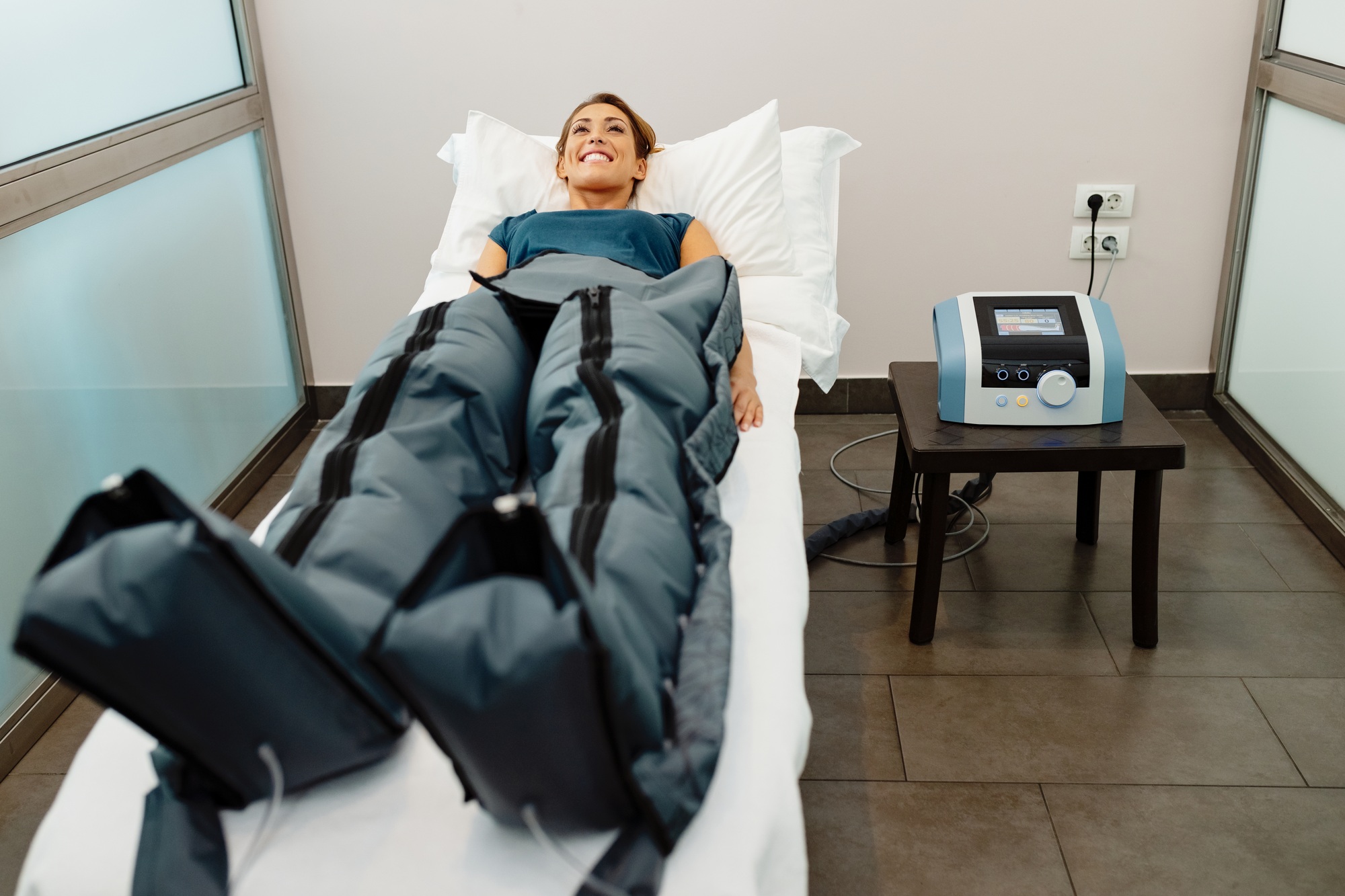 Happy woman during pressotherapy treatment at health spa.