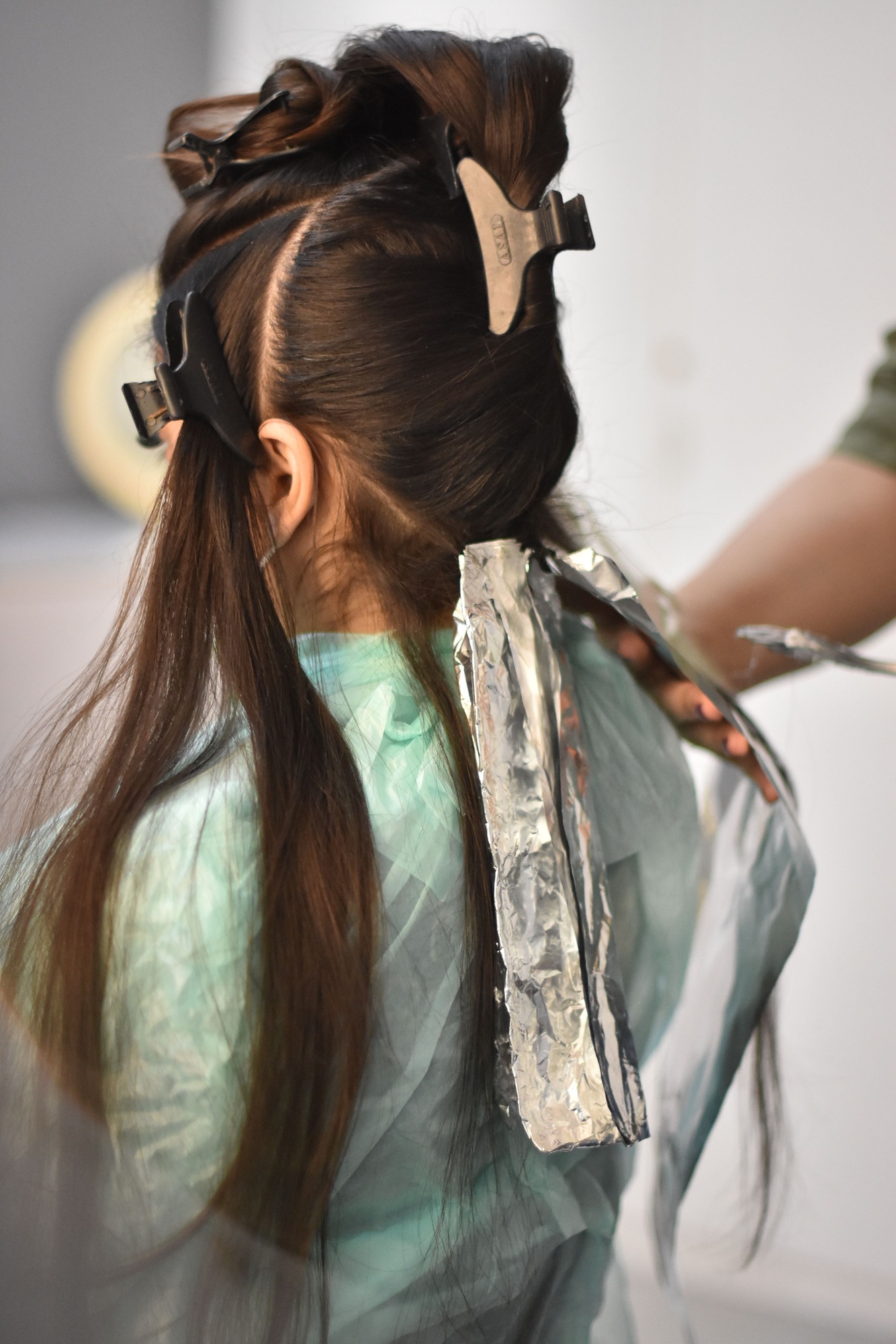 Vertical shot of a young girl doing her hair with the new balayage technique